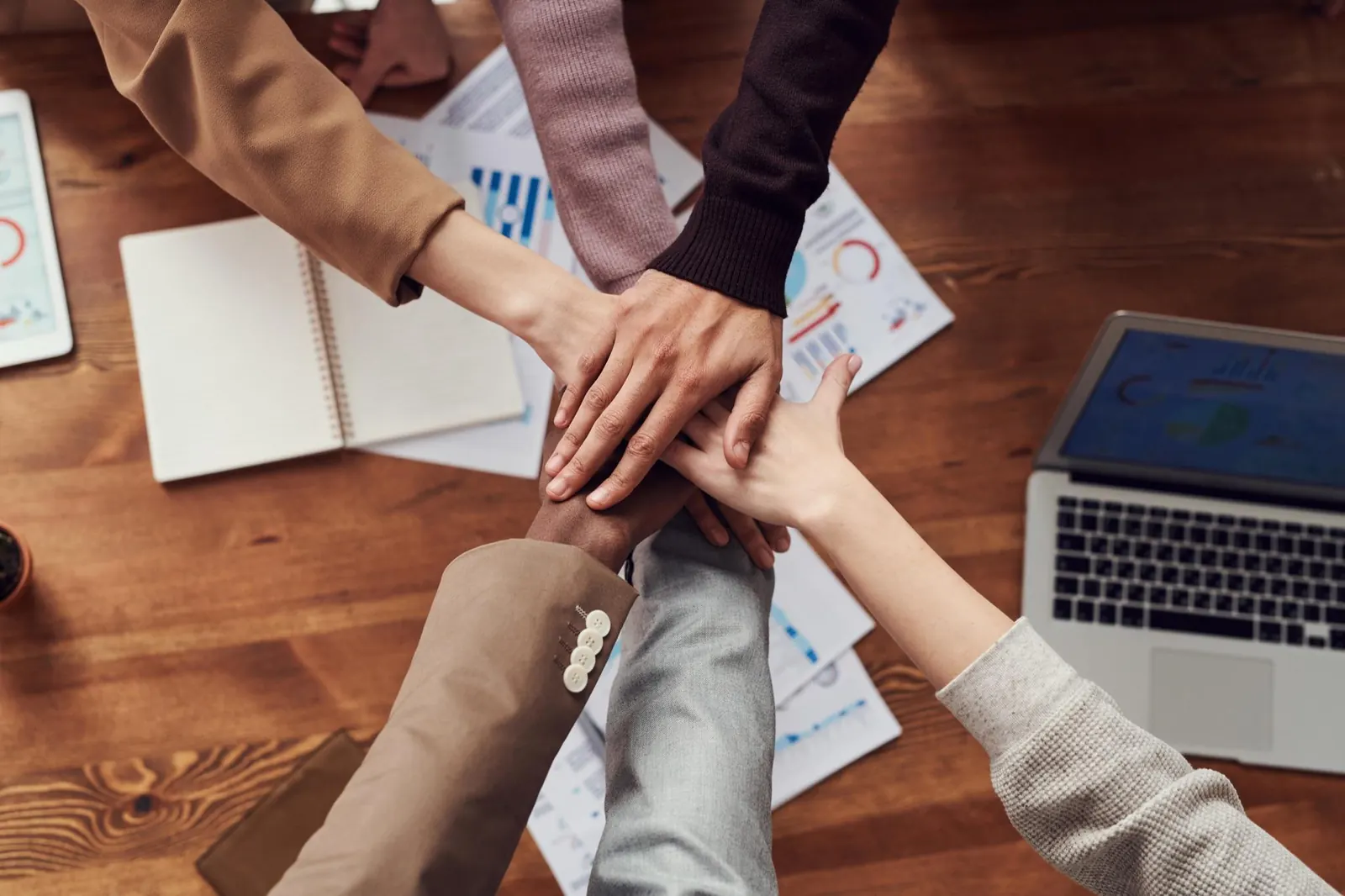 Equipo uniendo las manos sobre una mesa de trabajo